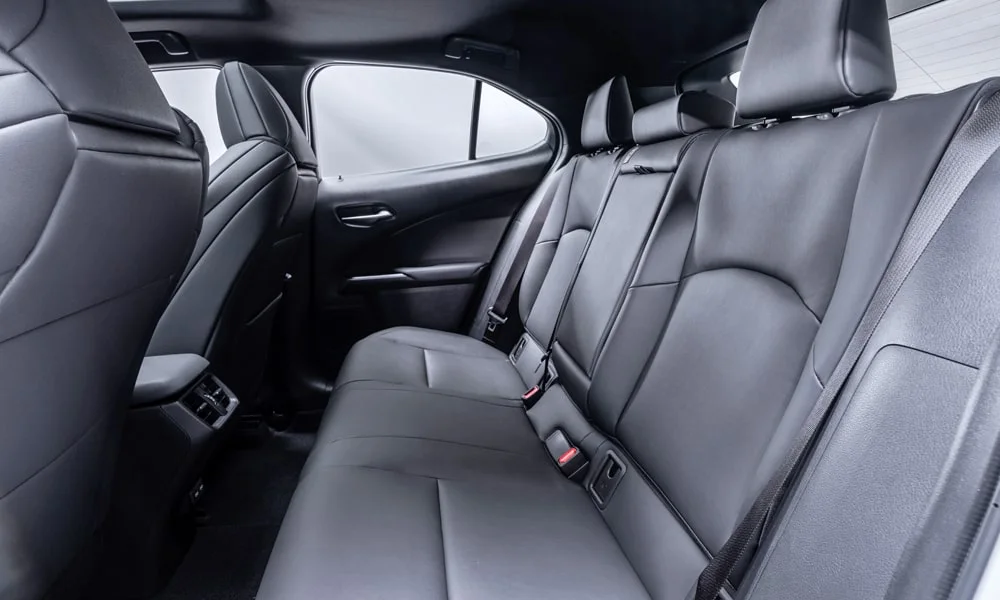 Фото Lexus UX 250h (2024) — задние сиденья. Посадка второго ряда: подголовники и подлокотник. Спинки складываются под длинные грузы у большинства версий Lexus UX 250h (2024) — задние сиденья