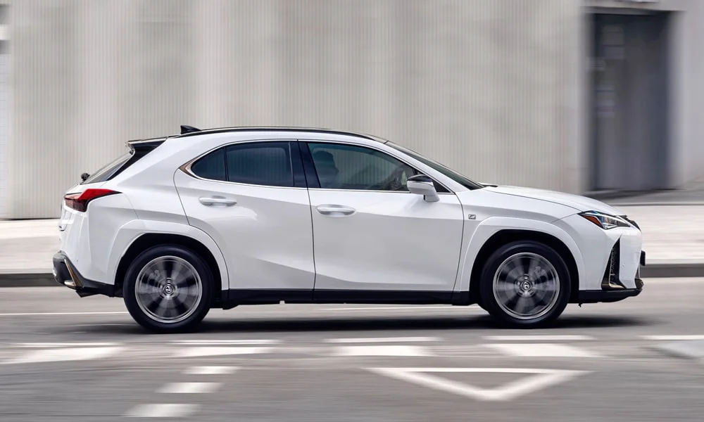 Фото Lexus UX 250h (2024) — вид сбоку, фото 2. Профиль в белом цвете: соотношение колёсной базы и свесов. Длинная база — простор второго ряда; короткие свесы упрощают парковку Lexus UX 250h (2024) — вид сбоку, фото 2