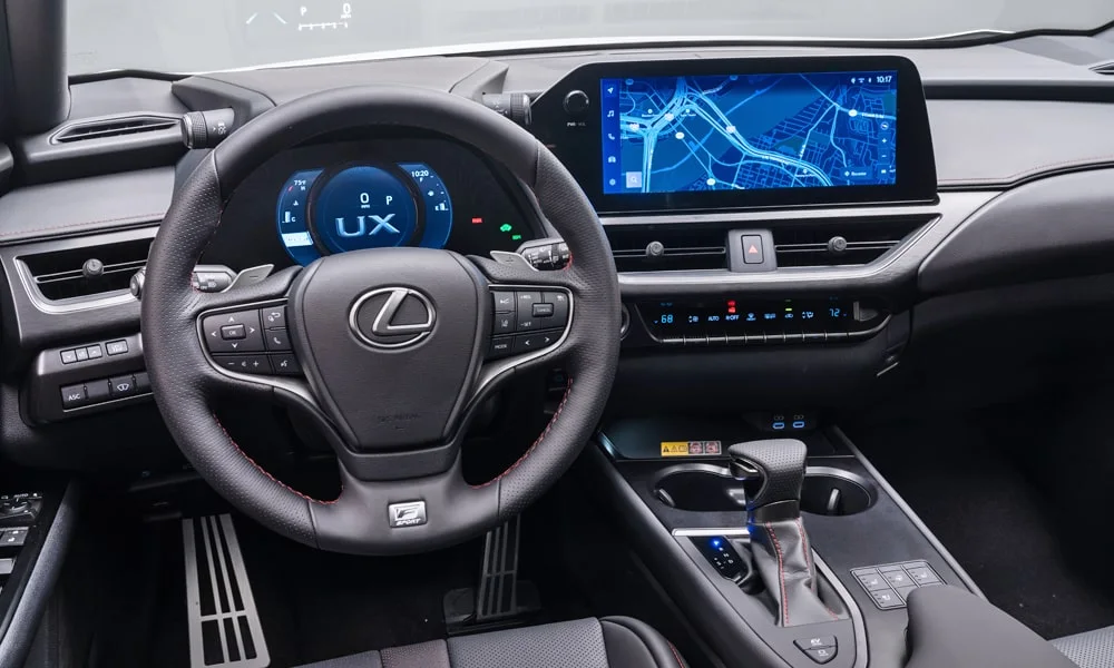 Фото Lexus UX 250h (2024) — руль. Обшивка обода и компоновка спиц крупным планом. Клавиши на спицах управляют медиа, круизом и ассистентами — руки остаются на руле Lexus UX 250h (2024) — руль