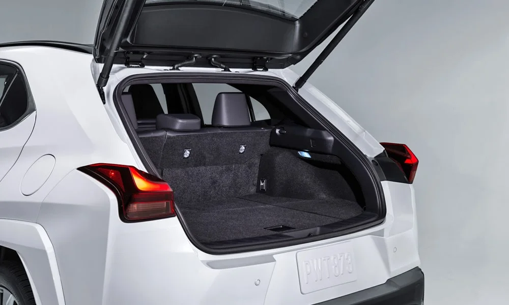 Фото Lexus UX 250h (2024) — багажник. Грузовой отсек с открытой дверью: погрузочная высота и ширина проёма. Спинки второго ряда складываются и расширяют отсек под длинные грузы Lexus UX 250h (2024) — багажник