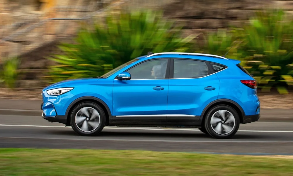 Фото MG ZS EV (2024) — вид сбоку, фото 3. Профиль в синем цвете: соотношение колёсной базы и свесов. Хромированные или чёрные молдинги окон отличают комплектации MG ZS EV (2024) — вид сбоку, фото 3