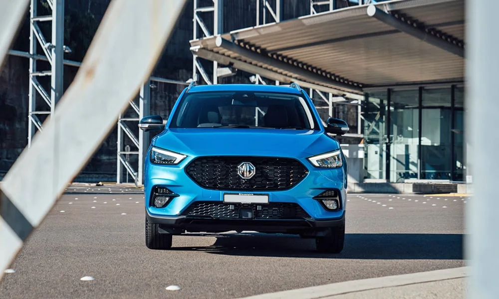 Фото MG ZS (2024) — вид спереди, фото 8. Синий кузов, строгая симметрия оптики — базовый ракурс знакомства с дизайном. Дневные ходовые огни включаются автоматически с запуском MG ZS (2024) — вид спереди, фото 8