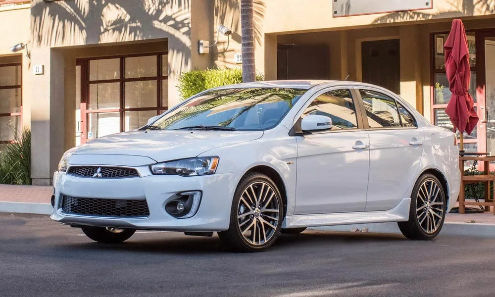 Фото Mitsubishi Lancer — вид спереди, фото 6. Кузов в белом цвете: рисунок оптики и решётки задаёт узнаваемое «лицо» модели. Дневные ходовые огни включаются автоматически с запуском Mitsubishi Lancer — вид спереди, фото 6