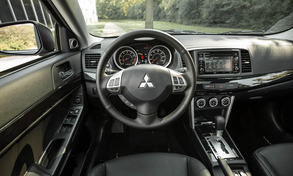 Фото Mitsubishi Lancer — руль. Обшивка обода и компоновка спиц крупным планом. Правильная посадка: руки на «9 и 3», приборы читаются поверх обода Mitsubishi Lancer — руль