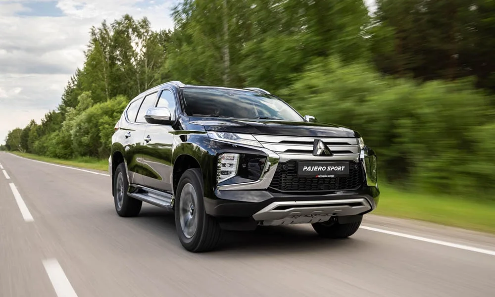 Фото Mitsubishi Pajero Sport — вид спереди, фото 7. Кузов в чёрном цвете: рисунок оптики и решётки задаёт узнаваемое «лицо» модели. Дневные ходовые огни включаются автоматически с запуском Mitsubishi Pajero Sport — вид спереди, фото 7