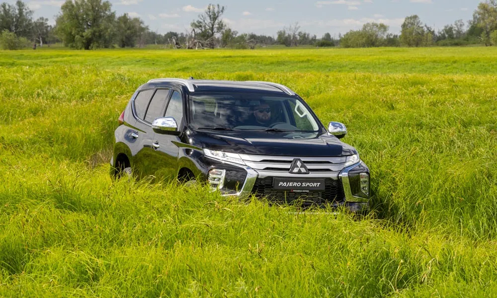 Фото Mitsubishi Pajero Sport — вид спереди, фото 8. Кузов в чёрном цвете: рисунок оптики и решётки задаёт узнаваемое «лицо» модели. Рисунок ходовых огней — подпись модели, по нему её узнают в потоке Mitsubishi Pajero Sport — вид спереди, фото 8