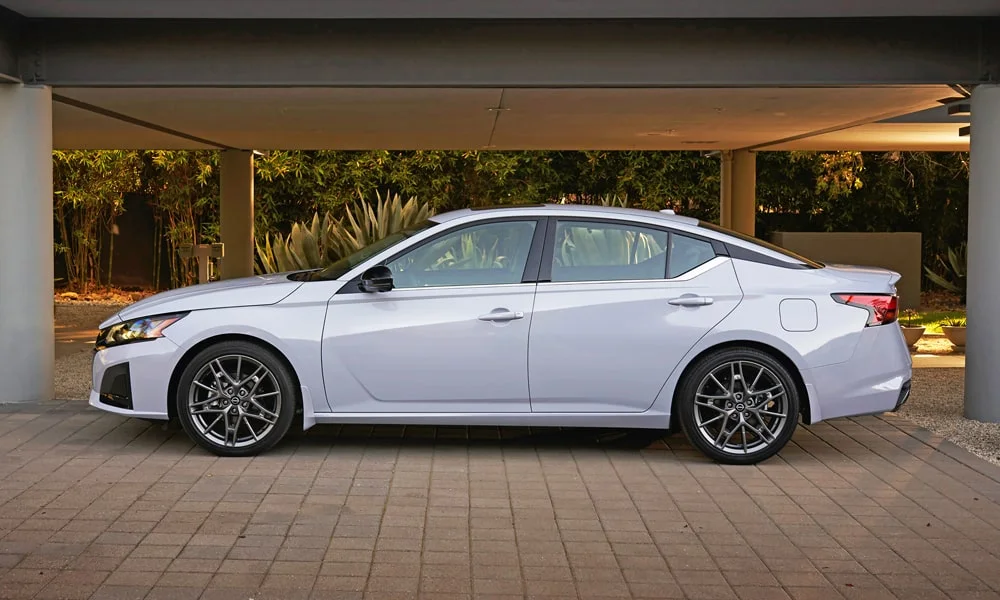 Фото Nissan Altima (2024) — вид сбоку, фото 3. Профиль в белом цвете: соотношение колёсной базы и свесов. Хромированные или чёрные молдинги окон отличают комплектации Nissan Altima (2024) — вид сбоку, фото 3