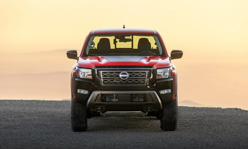 Фото Nissan Frontier (2024) — вид спереди, фото 5. Кузов в красном цвете: рисунок оптики и решётки задаёт узнаваемое «лицо» модели. Рисунок ходовых огней — подпись модели, по нему её узнают в потоке Nissan Frontier (2024) — вид спереди, фото 5