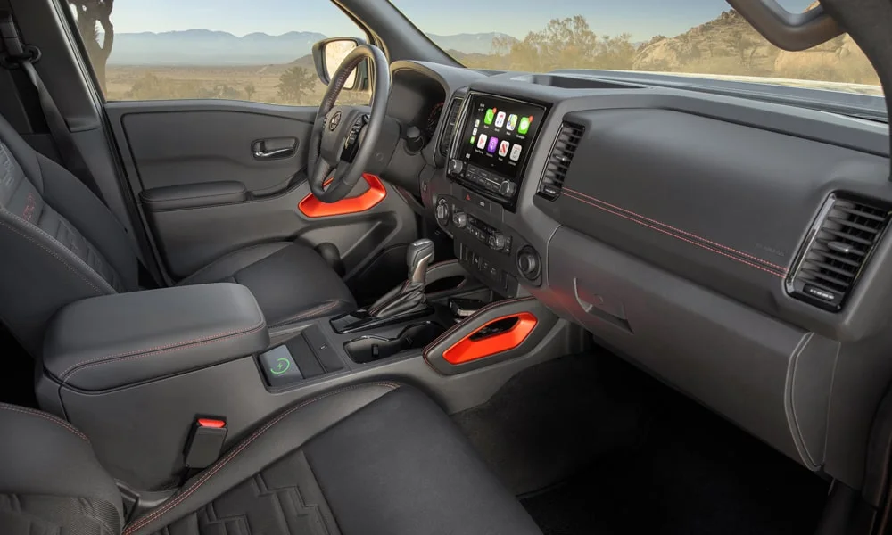 Фото Nissan Frontier (2024) — интерьер. Общий план салона: архитектура панели, консоль и кресла. Уровень отделки читается по стыкам панелей и мягким поверхностям в зонах касания Nissan Frontier (2024) — интерьер