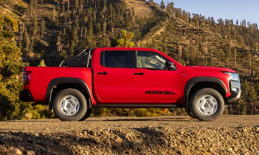 Фото Nissan Frontier (2024) — вид сбоку, фото 2. Красный кузов в профиль — пропорции, высота посадки и дизайн дисков. Хромированные или чёрные молдинги окон отличают комплектации Nissan Frontier (2024) — вид сбоку, фото 2