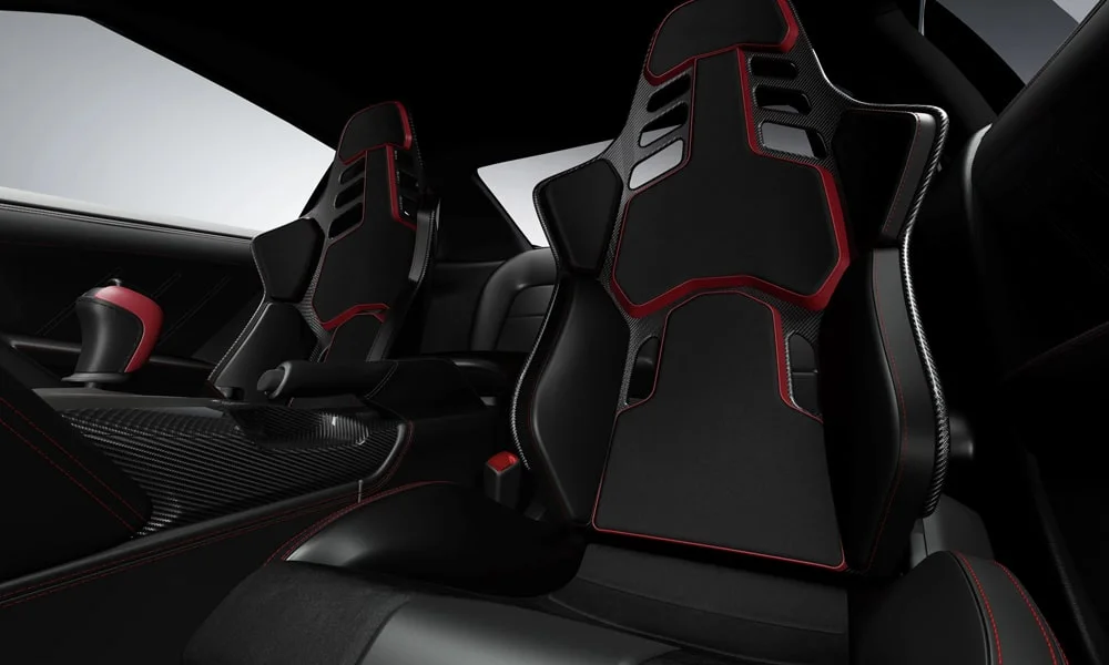 Фото Nissan GT-R — передние сиденья. Водительское и пассажирское кресла: обивка из перфорированной коже, профиль с боковой поддержкой. Регулировки с памятью возвращают кресло под водителя одним нажатием — у версий с электроприводом Nissan GT-R — передние сиденья