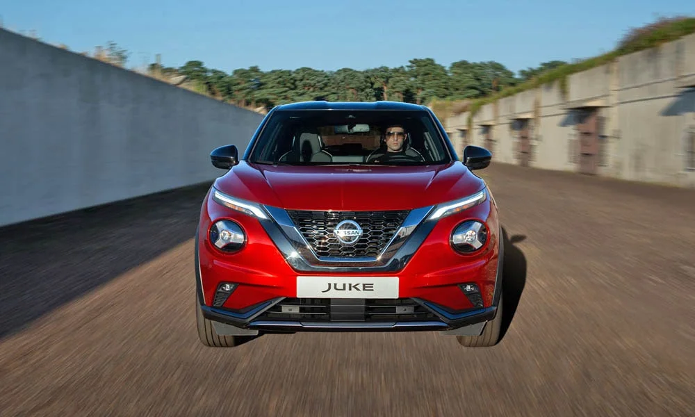 Фото Nissan Juke (2024) — вид спереди, фото 8. Красный кузов, строгая симметрия оптики — базовый ракурс знакомства с дизайном. Рисунок ходовых огней — подпись модели, по нему её узнают в потоке Nissan Juke (2024) — вид спереди, фото 8