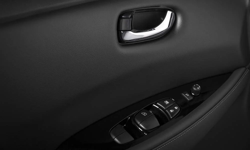Фото Nissan Leaf — дверная карта. Дверная карта в тёмной отделке: подлокотник, динамик и блок стеклоподъёмников. Решётка динамика в двери — часть штатной акустики Nissan Leaf — дверная карта