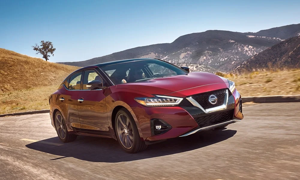 Фото Nissan Maxima — вид спереди, фото 4. Красный кузов, строгая симметрия оптики — базовый ракурс знакомства с дизайном. Дневные ходовые огни включаются автоматически с запуском Nissan Maxima — вид спереди, фото 4