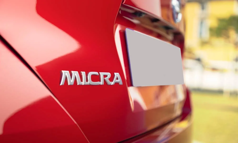 Фото Nissan Micra — эмблема, фото 2. Фирменный шильдик на кузове — знак принадлежности к марке. Шильдик версии на корме помогает отличать комплектации Nissan Micra — эмблема, фото 2