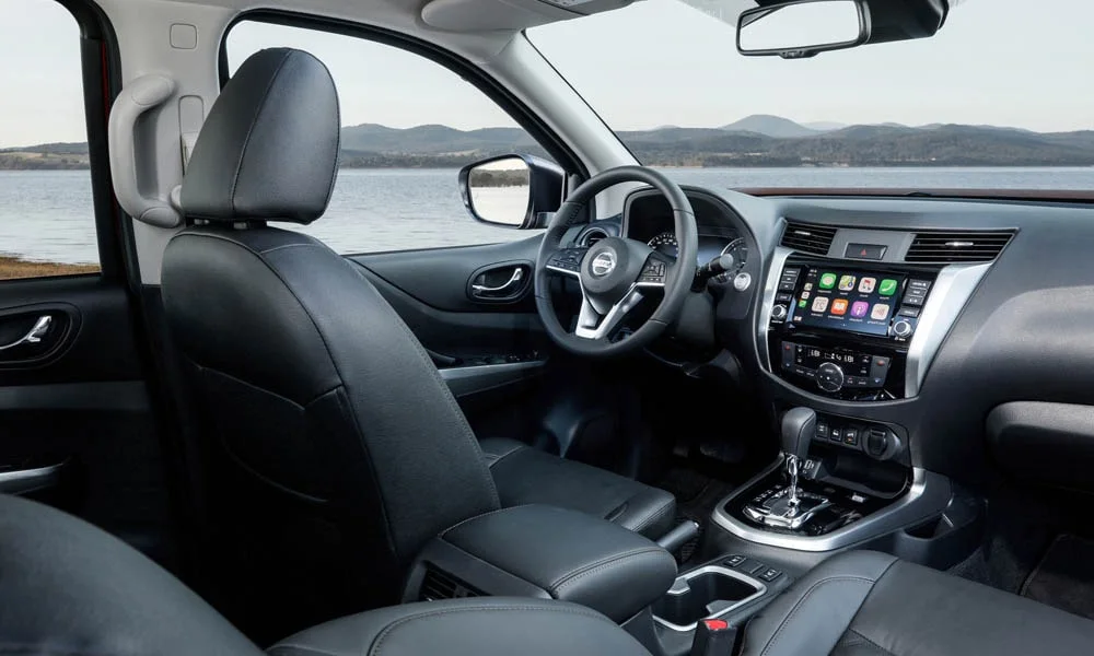 Фото Nissan Navara — передняя панель. Панель в тёмной отделке — видна компоновка экранов и органов управления. Минимум физических кнопок — ставка на экранное управление Nissan Navara — передняя панель