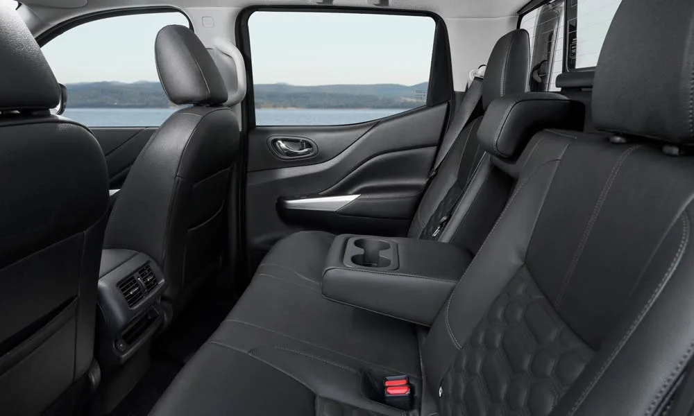 Фото Nissan Navara — задние сиденья. Посадка второго ряда: подголовники и подлокотник. Спинки складываются под длинные грузы у большинства версий Nissan Navara — задние сиденья