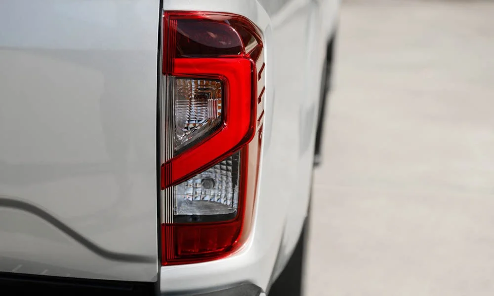 Фото Nissan Navara — задние фонари. Рассеиватель фонаря вблизи: компоновка секций габарита, стопа и поворотника. Динамические поворотники с бегущей индикацией встречаются в старших комплектациях Nissan Navara — задние фонари