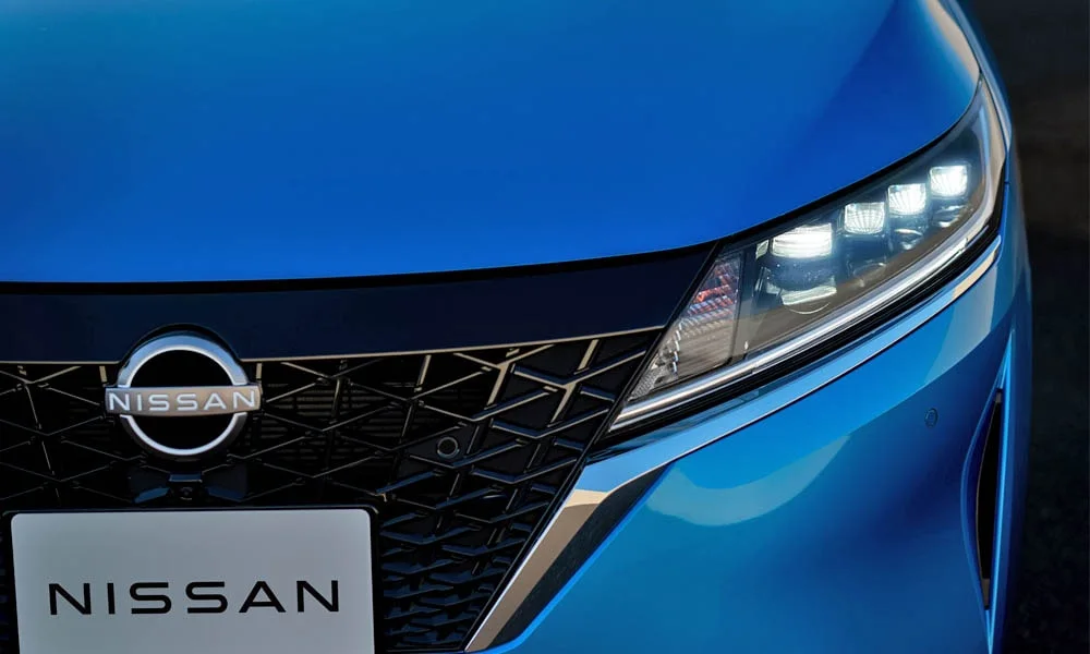 Фото Nissan Note — вид спереди, фото 5. Кузов в синем цвете: рисунок оптики и решётки задаёт узнаваемое «лицо» модели. Дневные ходовые огни включаются автоматически с запуском Nissan Note — вид спереди, фото 5