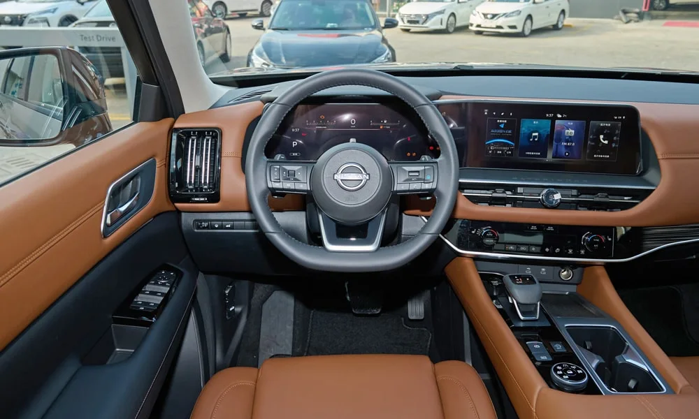 Фото Nissan Pathfinder (2022) — передняя панель. Архитектура передней панели: ярусы, вставки и консоль в коричневой гамме. Мягкие материалы верхнего яруса и вставки задают уровень интерьера Nissan Pathfinder (2022) — передняя панель