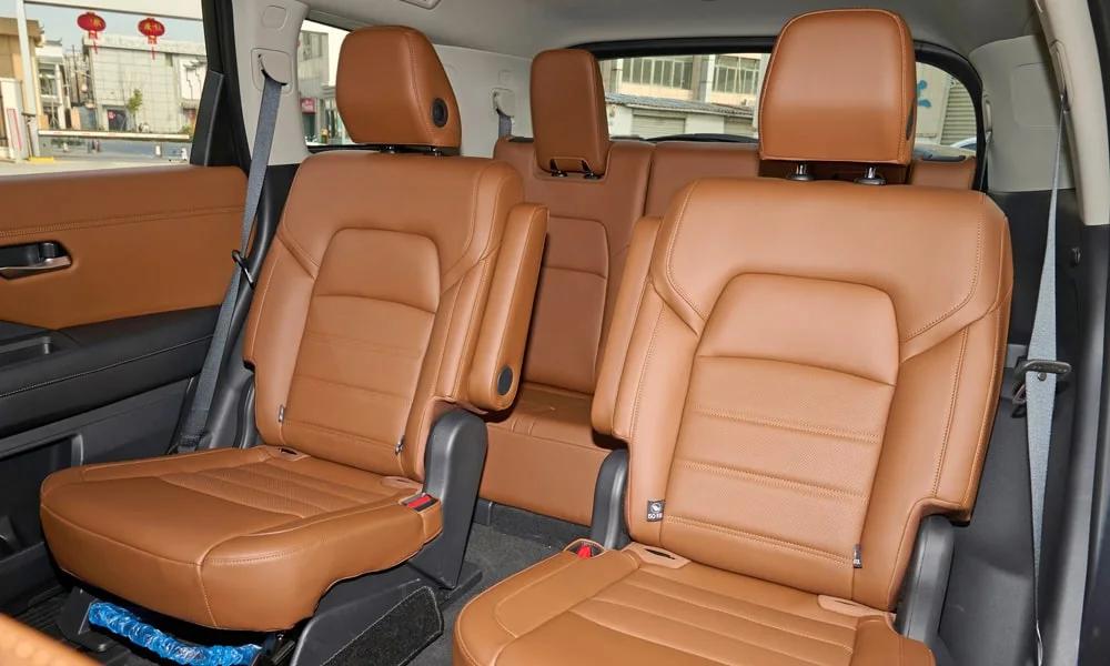 Фото Nissan Pathfinder (2022) — задние сиденья. Задний диван в гладкой коже: посадка и центральный подлокотник. Спинки складываются под длинные грузы у большинства версий Nissan Pathfinder (2022) — задние сиденья