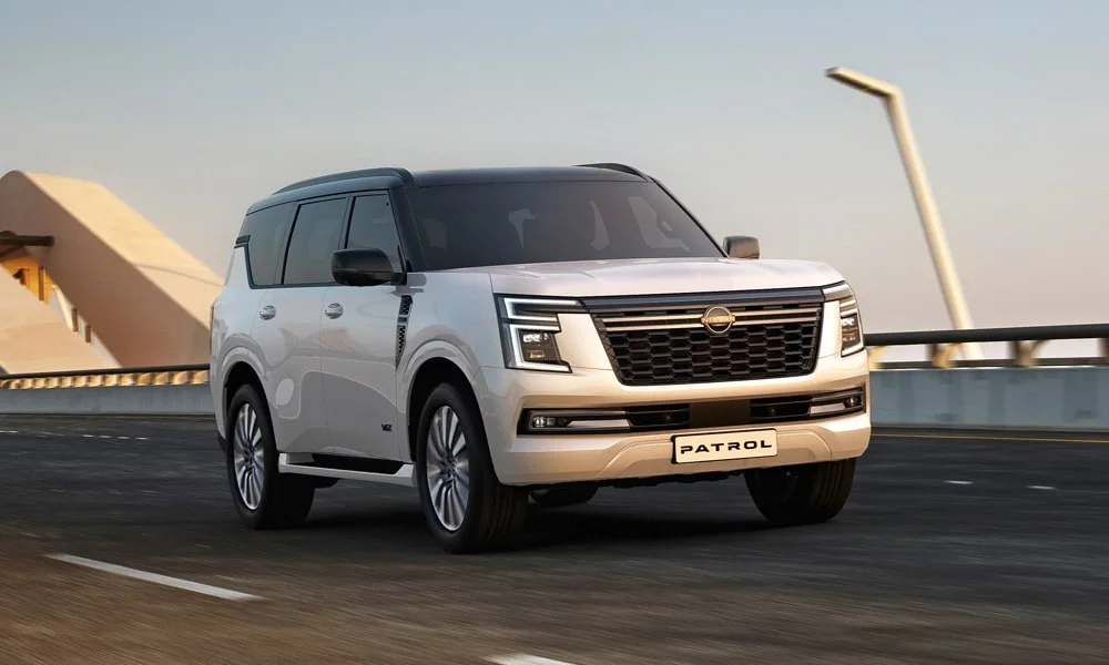 Фото Nissan Patrol (2024) — вид спереди, фото 3. Передок в белом исполнении — крупная светотехника и выразительный бампер. Рисунок ходовых огней — подпись модели, по нему её узнают в потоке Nissan Patrol (2024) — вид спереди, фото 3