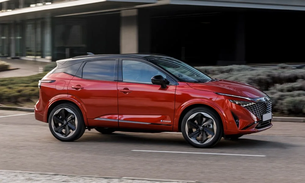 Фото Nissan Qashqai (2024) — вид сбоку, фото 3. Профиль в красном цвете: соотношение колёсной базы и свесов. Хромированные или чёрные молдинги окон отличают комплектации Nissan Qashqai (2024) — вид сбоку, фото 3