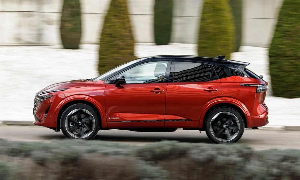 Фото Nissan Qashqai (2024) — вид сбоку, фото 4. Сбоку читаются линия остекления и характер выштамповок на красном кузове. Длинная база — простор второго ряда; короткие свесы упрощают парковку Nissan Qashqai (2024) — вид сбоку, фото 4
