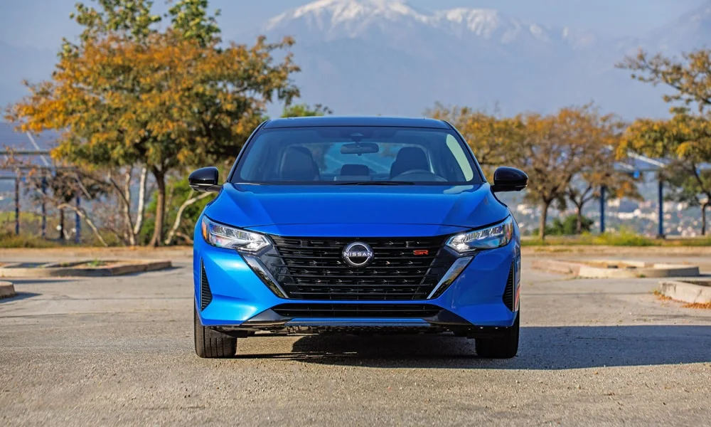 Фото Nissan Sentra — вид спереди, фото 3. Синий кузов, строгая симметрия оптики — базовый ракурс знакомства с дизайном. Дневные ходовые огни включаются автоматически с запуском Nissan Sentra — вид спереди, фото 3