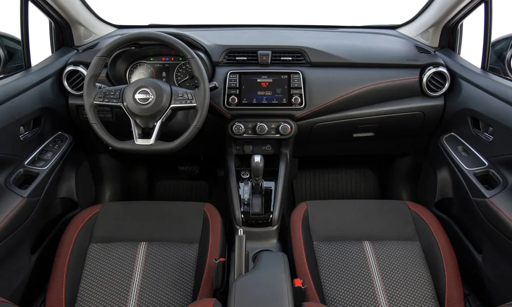 Фото Nissan Versa (2024) — передняя панель. Архитектура передней панели: ярусы, вставки и консоль в красно-чёрной гамме. Мягкие материалы верхнего яруса и вставки задают уровень интерьера Nissan Versa (2024) — передняя панель