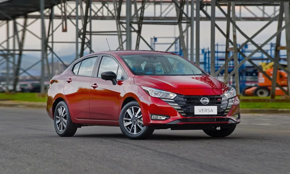 Фото Nissan Versa (2024) — вид спереди, фото 5. Передок в красном исполнении — крупная светотехника и выразительный бампер. Рисунок ходовых огней — подпись модели, по нему её узнают в потоке Nissan Versa (2024) — вид спереди, фото 5