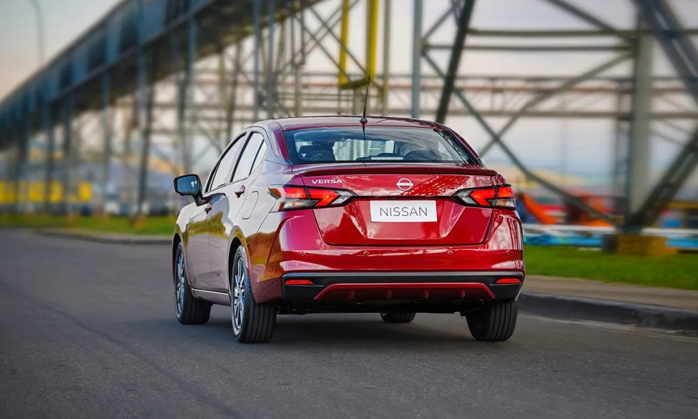 Фото Nissan Versa (2024) — вид сзади, фото 3. Красный кузов сзади — фонари и бампер определяют ночной образ модели. Светодиодная полоса или раздельные секции — задняя оптика стала главным украшением кормы Nissan Versa (2024) — вид сзади, фото 3