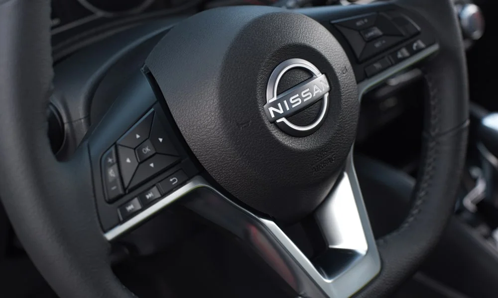 Фото Nissan Versa (2024) — руль, фото 2. Обшивка обода и компоновка спиц крупным планом. Клавиши на спицах управляют медиа, круизом и ассистентами — руки остаются на руле Nissan Versa (2024) — руль, фото 2