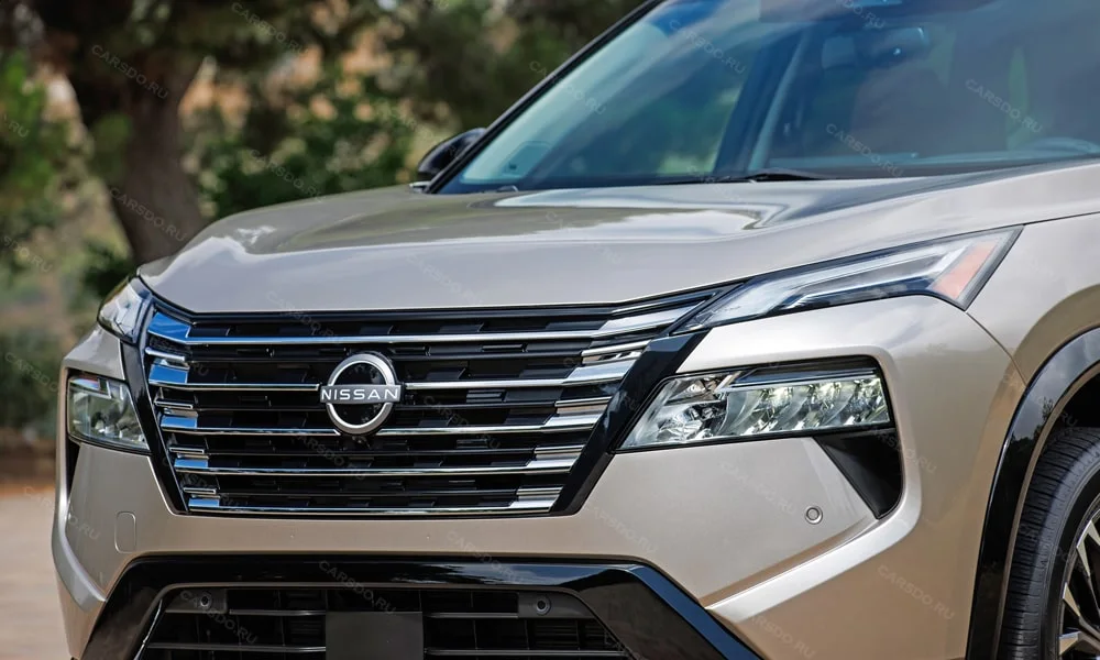 Фото Nissan X-Trail (2024) — решётка радиатора. Фирменный рисунок облицовки — визитная карточка марки Nissan X-Trail (2024) — решётка радиатора