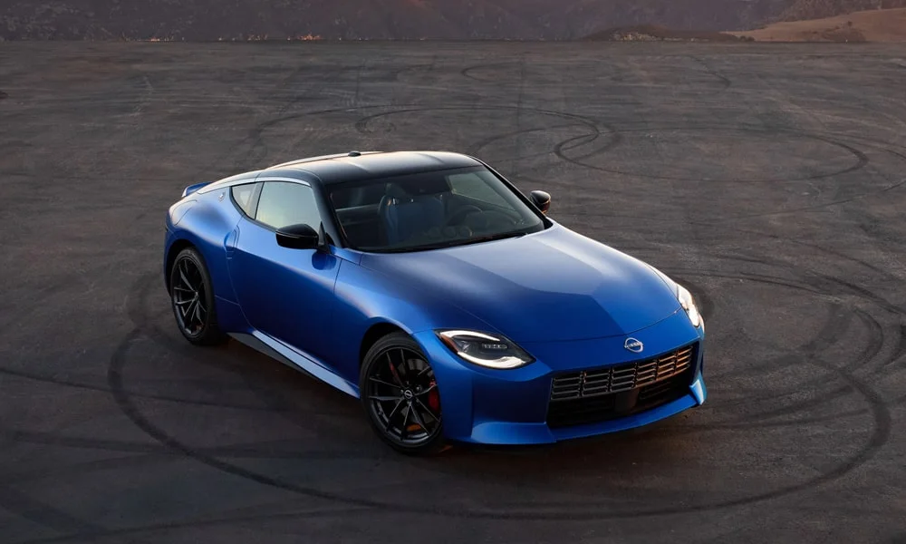Фото Nissan Z (2024) — вид спереди, фото 12. Кузов в синем цвете: рисунок оптики и решётки задаёт узнаваемое «лицо» модели. Рисунок ходовых огней — подпись модели, по нему её узнают в потоке Nissan Z (2024) — вид спереди, фото 12