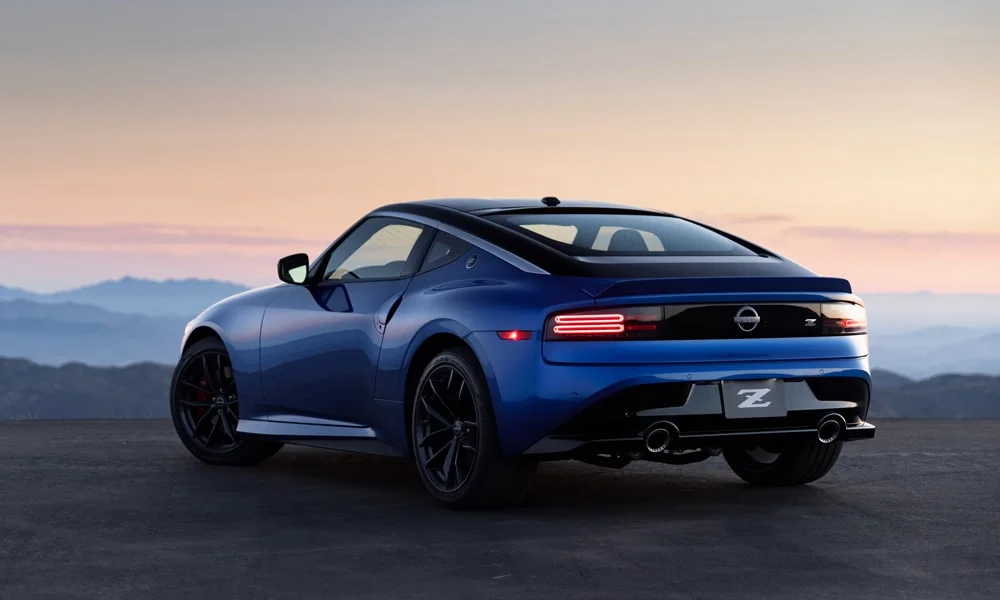 Фото Nissan Z (2024) — вид сзади, фото 6. Линия крыши, стойки и задняя дверь в синем исполнении. Насадки выхлопа или их имитация внизу бампера различают версии Nissan Z (2024) — вид сзади, фото 6