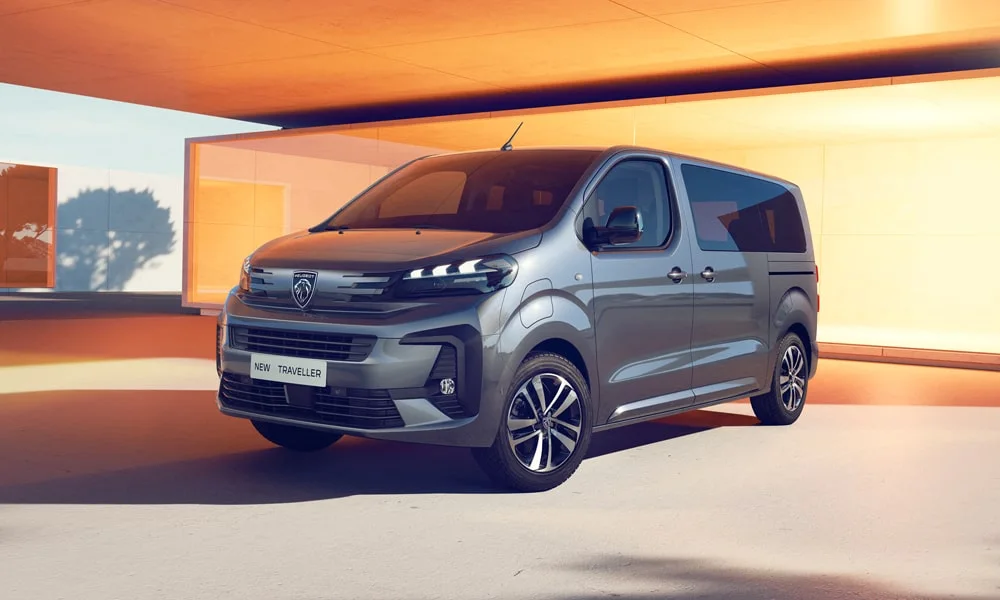 Фото Peugeot Traveller (2024) — вид спереди, фото 6. Кузов в сером цвете: рисунок оптики и решётки задаёт узнаваемое «лицо» модели. Рисунок ходовых огней — подпись модели, по нему её узнают в потоке Peugeot Traveller (2024) — вид спереди, фото 6