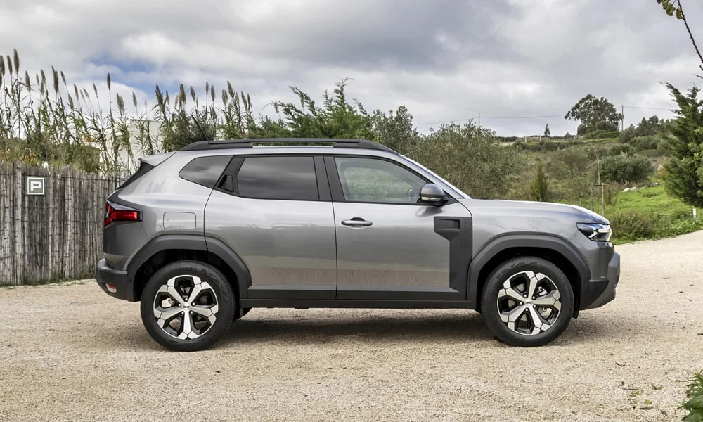 Фото Renault Duster (2024) — вид сбоку, фото 2. Профиль кузова: колёсная база, свесы и линия остекления. Хромированные или чёрные молдинги окон отличают комплектации Renault Duster (2024) — вид сбоку, фото 2