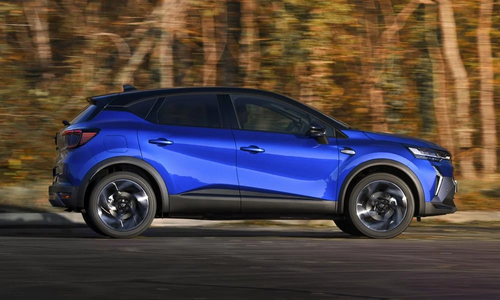 Фото Renault Kaptur (2024) — вид сбоку, фото 4. Профиль в синем цвете: соотношение колёсной базы и свесов. Хромированные или чёрные молдинги окон отличают комплектации Renault Kaptur (2024) — вид сбоку, фото 4