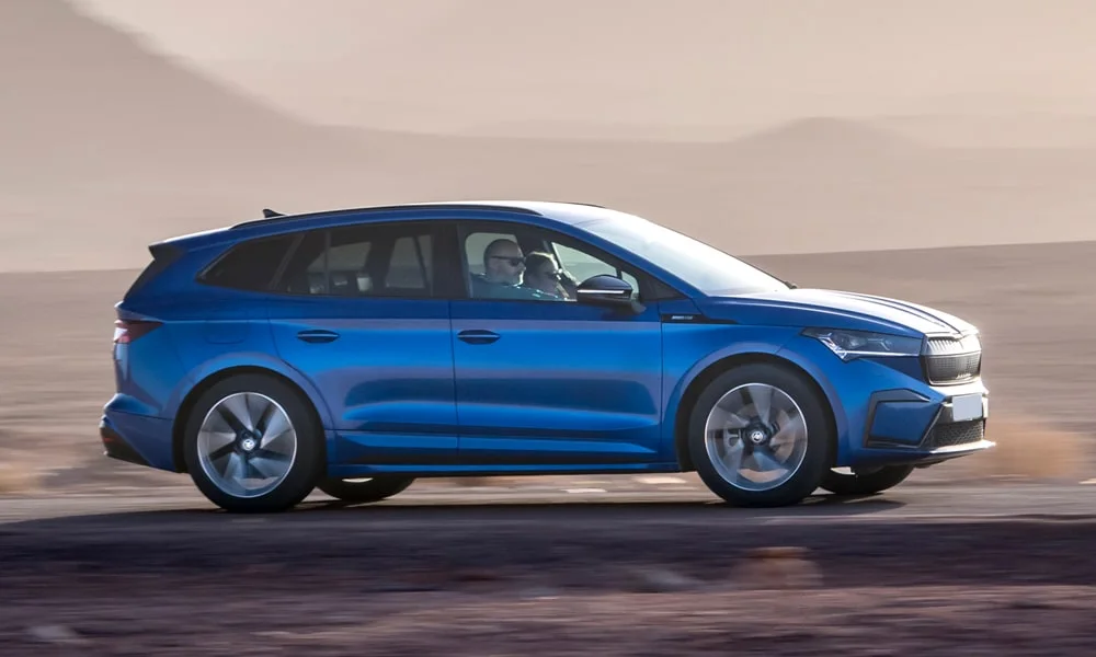 Фото Skoda Enyaq (2024) — вид сбоку, фото 3. Синий кузов в профиль — пропорции, высота посадки и дизайн дисков. Хромированные или чёрные молдинги окон отличают комплектации Skoda Enyaq (2024) — вид сбоку, фото 3