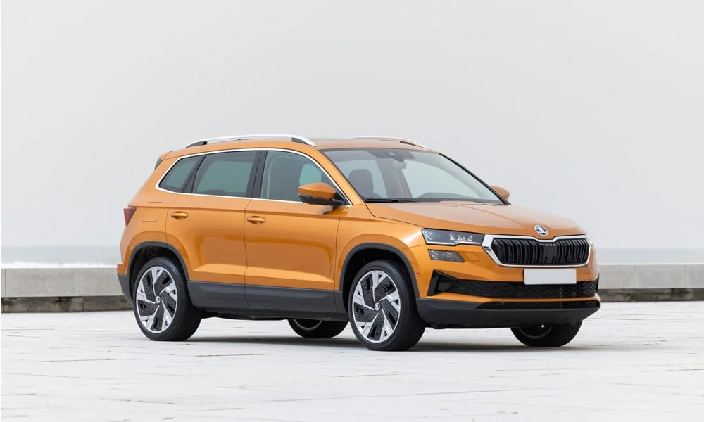 Фото Skoda Karoq (2024) — вид спереди, фото 3. Оранжевый кузов, строгая симметрия оптики — базовый ракурс знакомства с дизайном Skoda Karoq (2024) — вид спереди, фото 3