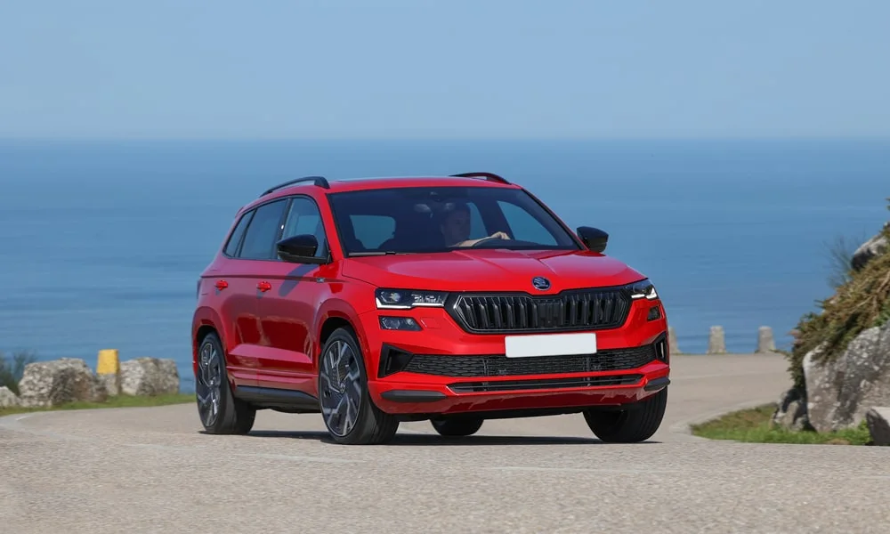 Фото Skoda Karoq (2024) — вид спереди, фото 4. Красный кузов, строгая симметрия оптики — базовый ракурс знакомства с дизайном. Дневные ходовые огни включаются автоматически с запуском Skoda Karoq (2024) — вид спереди, фото 4