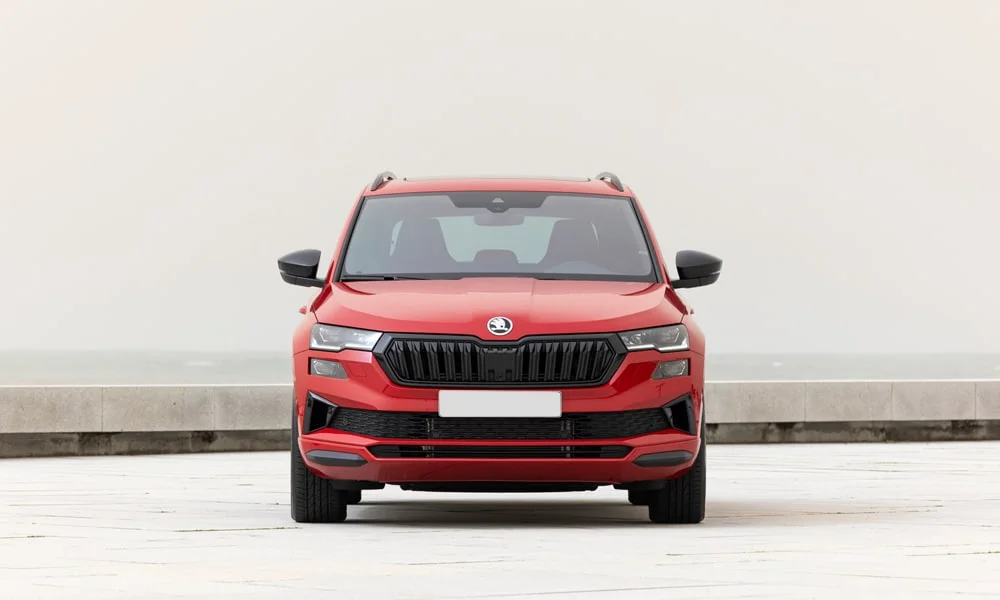 Фото Skoda Karoq (2024) — вид спереди, фото 7. Красный кузов, строгая симметрия оптики — базовый ракурс знакомства с дизайном. Дневные ходовые огни включаются автоматически с запуском Skoda Karoq (2024) — вид спереди, фото 7