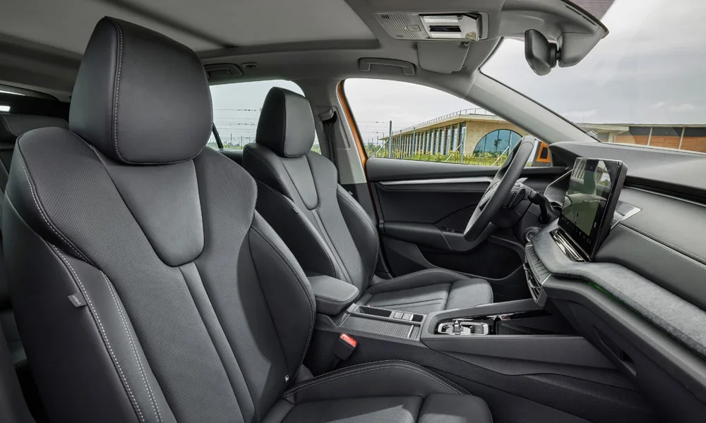Фото Skoda Octavia Combi (2024) — интерьер, фото 3. Салон в тёмной отделке: архитектура передней панели, консоль и кресла. Уровень отделки читается по стыкам панелей и мягким поверхностям в зонах касания Skoda Octavia Combi (2024) — интерьер, фото 3