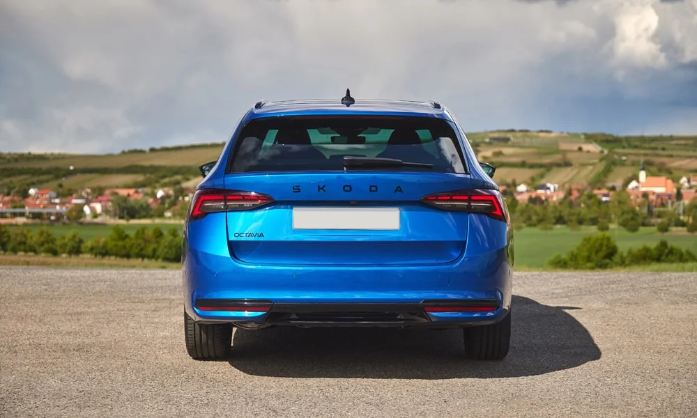 Фото Skoda Octavia Combi (2024) — вид сзади, фото 5. Синий кузов сзади — фонари и бампер определяют ночной образ модели. Насадки выхлопа или их имитация внизу бампера различают версии Skoda Octavia Combi (2024) — вид сзади, фото 5