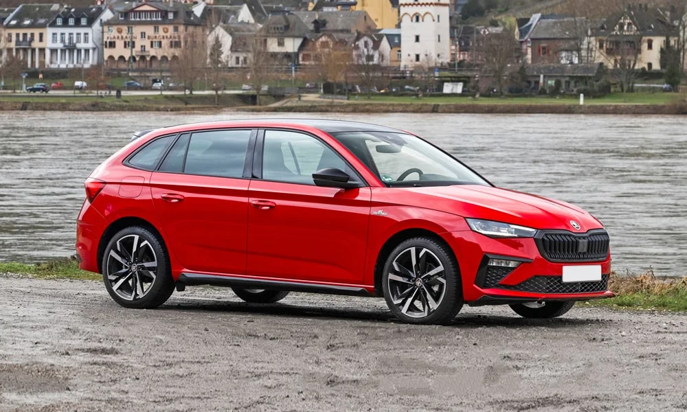 Фото Skoda Scala (2024) — вид спереди, фото 10. Красный кузов, строгая симметрия оптики — базовый ракурс знакомства с дизайном. Рисунок ходовых огней — подпись модели, по нему её узнают в потоке Skoda Scala (2024) — вид спереди, фото 10