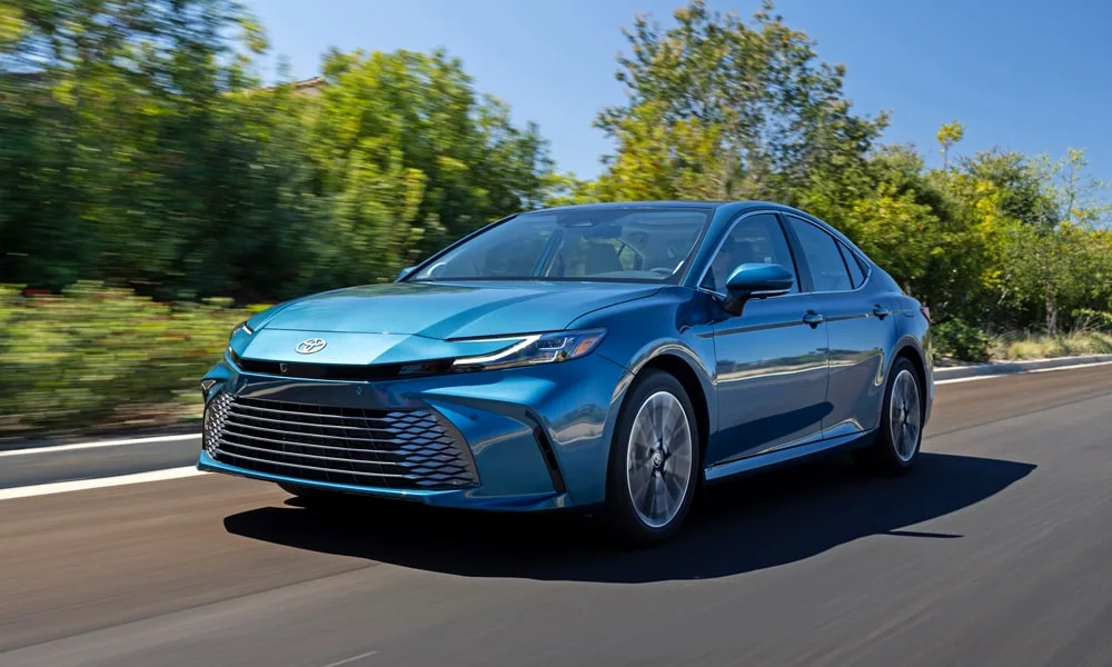 Фото Toyota Camry (2024) — вид спереди, фото 6. Синий кузов, строгая симметрия оптики — базовый ракурс знакомства с дизайном Toyota Camry (2024) — вид спереди, фото 6