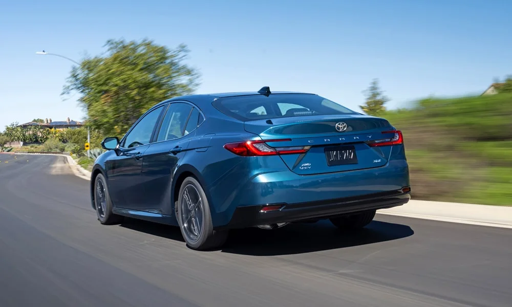 Фото Toyota Camry (2024) — вид сзади, фото 6. Линия крыши, стойки и задняя дверь в синем исполнении. Насадки выхлопа или их имитация внизу бампера различают версии Toyota Camry (2024) — вид сзади, фото 6