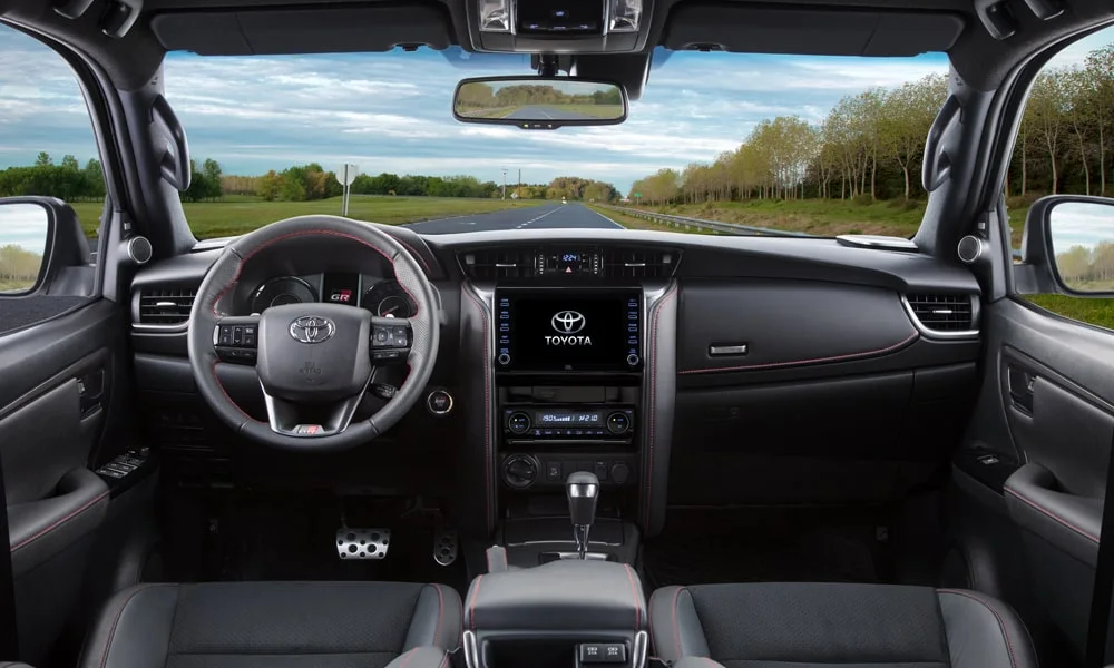 Фото Toyota Fortuner (2024) — передняя панель. Передняя панель в тёмной отделке: расположение экранов и дефлекторов. Минимум физических кнопок — ставка на экранное управление Toyota Fortuner (2024) — передняя панель