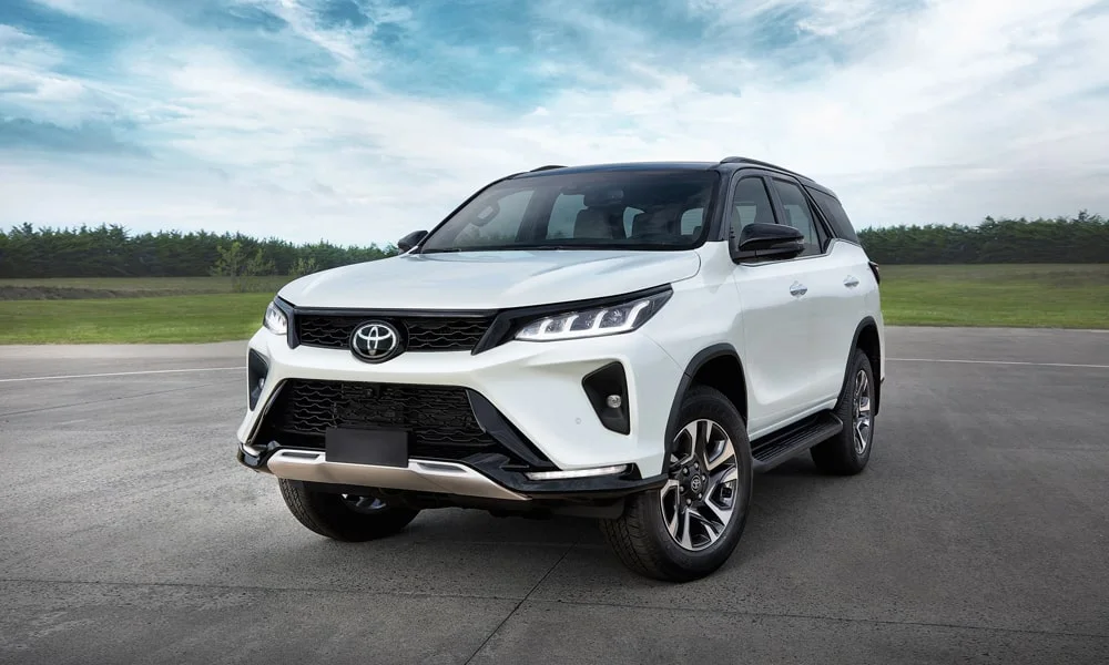 Фото Toyota Fortuner (2024) — вид спереди, фото 5. Белый кузов, строгая симметрия оптики — базовый ракурс знакомства с дизайном. Рисунок ходовых огней — подпись модели, по нему её узнают в потоке Toyota Fortuner (2024) — вид спереди, фото 5